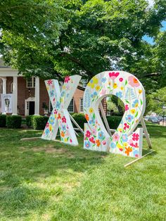 the large letters are decorated with flowers in front of a brick building and trees on the lawn