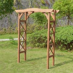 an outdoor wooden arbor in the grass