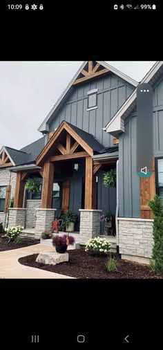 a gray house with wood trim and stone accents on the front porch, along with landscaping