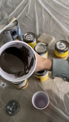 a person is holding a paint can and some cans