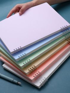 a stack of notebooks with a person's hand resting on one of them