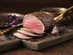 sliced meat sitting on top of a wooden cutting board