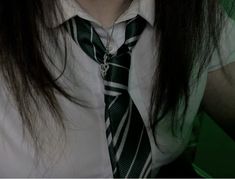 a woman wearing a tie and white shirt with green stripes on her collar, posing for the camera