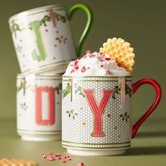 two coffee mugs filled with whipped cream and candy canes next to each other