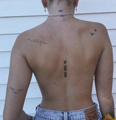 a woman with tattoos on her back holding a yellow flower