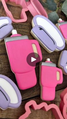 decorated cookies with pink and purple icing on wooden table next to cookie cutters