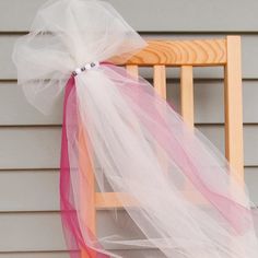 a chair with a pink and white tulle on it's back sitting in front of a house