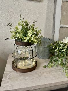 two vases filled with flowers sitting on top of a wooden table next to each other