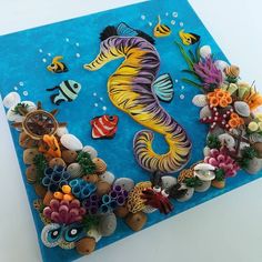 a seahorse made out of shells and other items on top of a blue surface