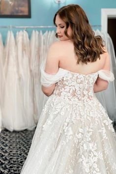 a woman in a wedding dress looking down at her gown