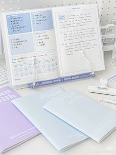 several notebooks and pens sitting on a table next to an open binder book