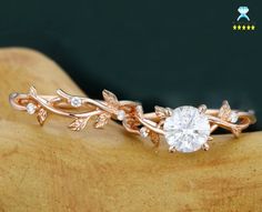 a close up of a ring on top of a wooden surface with leaves and diamonds