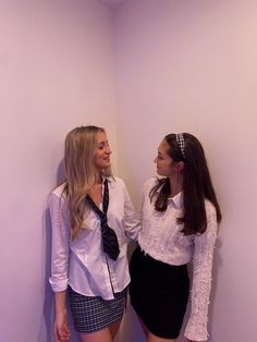 two young women standing next to each other in a room with purple walls and white walls