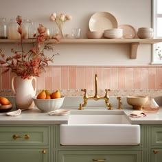 a kitchen with green cabinets and gold faucet, white counter tops and pink tiles