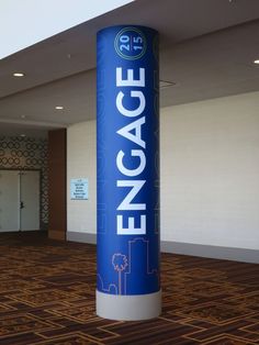 a large blue sign that says engage in front of a room with carpeted floors