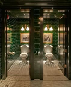 two toilets in a bathroom with green tiles on the walls and floor, surrounded by black doors