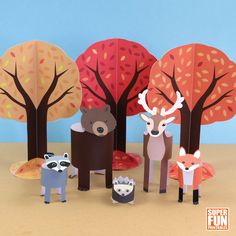 some paper animals are standing in front of trees with leaves on them and one animal is looking at the camera