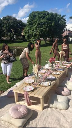 a group of people standing around a table with plates and cups on top of it