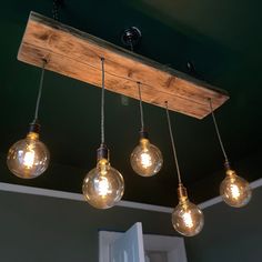 five light bulbs hanging from a wooden beam in a room with green walls and ceiling