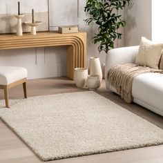 a living room with white furniture and a rug on the floor in front of a table