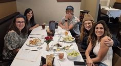 a group of people sitting at a table with food