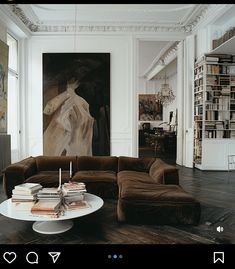 a living room filled with furniture next to a book shelf and a painting on the wall