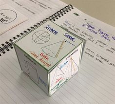 an open notebook with some writing on it and a cube shaped object in the middle