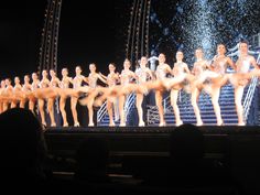 a large group of dancers on stage in front of a crowd