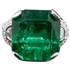 This vibrant Zambian emerald is set in a modified 3 stone style ring with 2 half moon diamonds on the sides with round brilliant diamonds finishing off the masterpiece. The lust, green emerald is the focal point and showcases amazing color in this platinum setting. The half moon diamonds are surrounded by smaller round brilliant diamonds that form a 3 stone style appearance. It is a must for anyone desiring a collectible emerald ring for their jewelry collection. Ring Size: 6.5 (can be sized) Em Luxury Exquisite Round Emerald Ring, African Inspired Jewelry, Golden Ring, Zambian Emerald, African Jewelry, Emerald Jewelry, Emerald Cut Diamonds, Green Emerald, Zambia