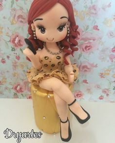 a little doll sitting on top of a yellow container with a cell phone in her hand