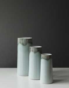 three white vases sitting on top of a table