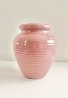 a pink vase sitting on top of a white table