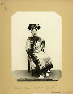 an old black and white photo of a woman in traditional chinese dress sitting on a chair