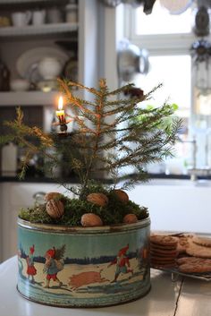 a tin can with a christmas tree in it and cookies on the table next to it