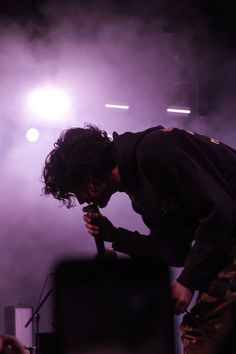 a man standing on top of a stage with his head in his hands while holding a microphone