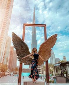 a woman standing in front of an angel statue