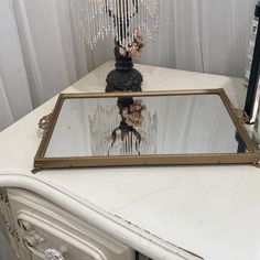 a mirror sitting on top of a white table next to a vase filled with flowers