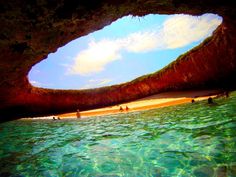 the water is crystal blue and clear with people walking on the beach in the distance