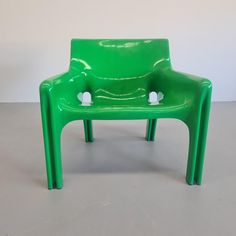 a green plastic chair sitting on top of a cement floor