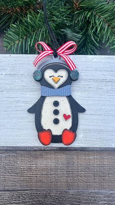 a snowman ornament is hanging on a wooden plank with pine branches in the background