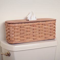 a basket sitting on top of a toilet next to a roll of white tissue paper