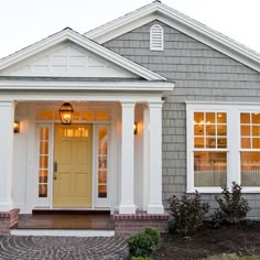 a gray house with white trim and yellow door