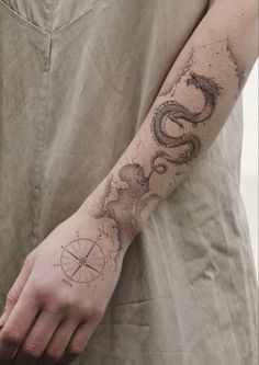 a man with a tattoo on his arm holding a compass and snake in the background