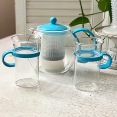 three glasses and a teapot sitting on a table