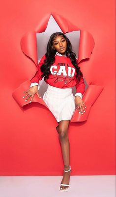 a woman in a red shirt and white skirt standing next to a wall with the word cau on it