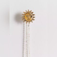 a gold sun and moon decoration hanging on a white wall next to some glass beads