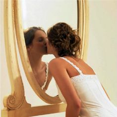 a woman in white dress kissing a mirror