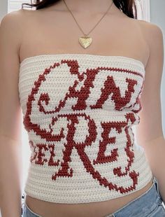 a woman wearing a red and white crochet top with a gold heart necklace