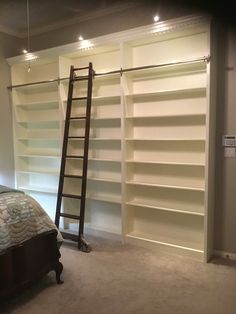 a ladder leaning against the wall next to a bed in a room with white shelving