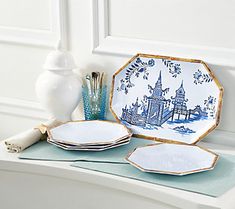 a table topped with plates and vases on top of a white counter next to a window